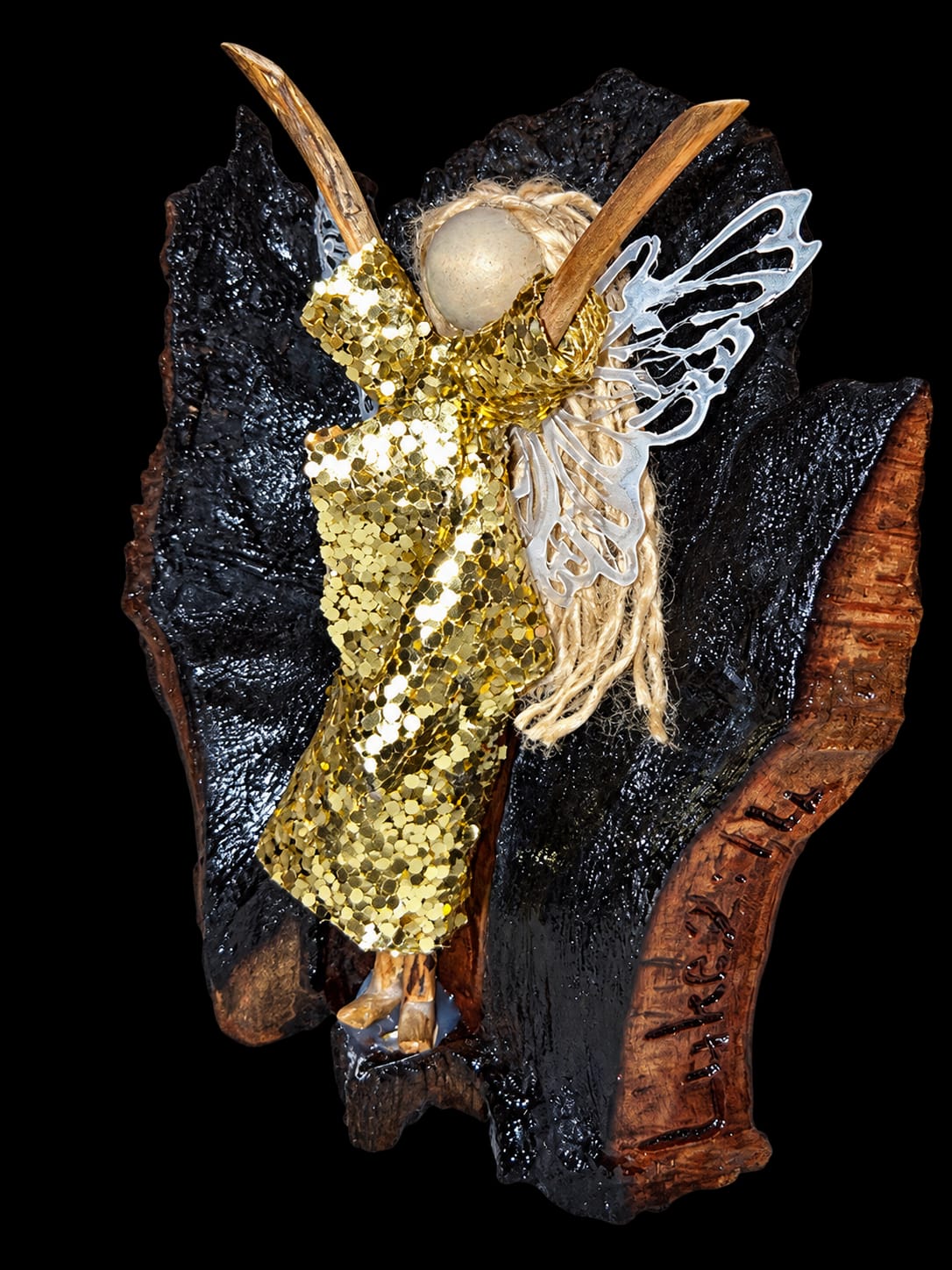 Golden handmade angel with raised arms and delicate wings on a dark wooden base
