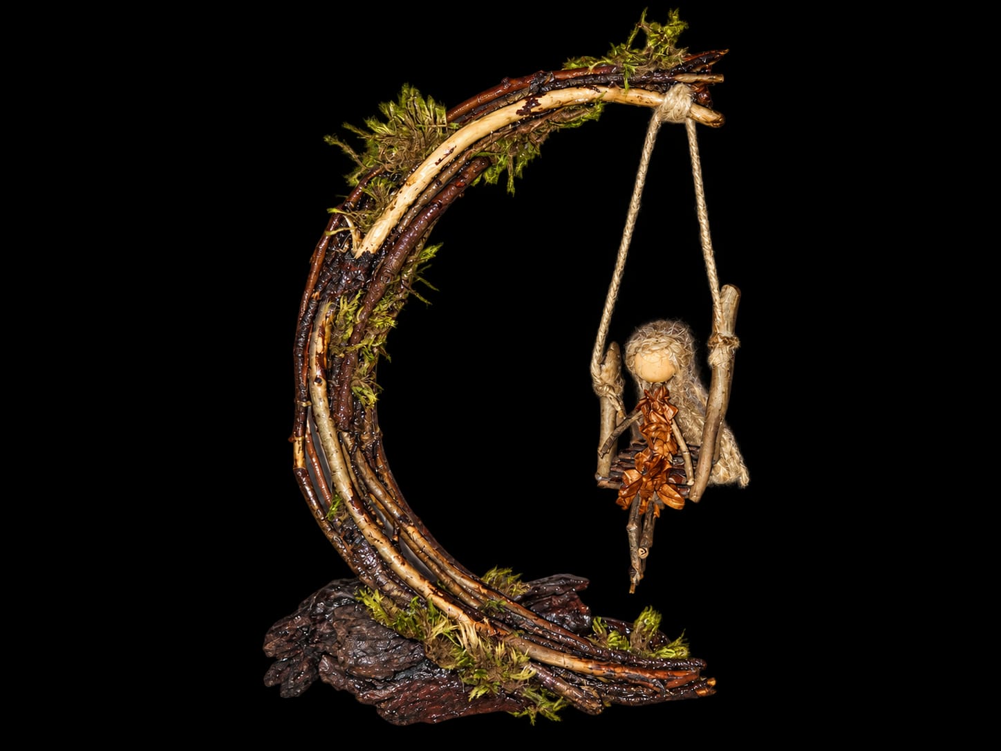 Handmade figure on a rope swing suspended beneath a curved wooden branch